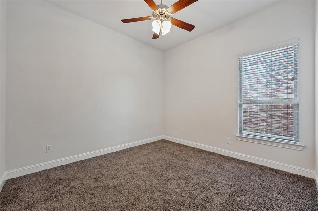 Neutral wall color, carpeted flooring, window with blinds, and a ceiling fan with integrated lighting