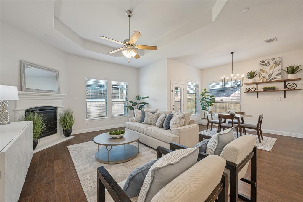 Tray ceiling, wood-finish flooring, fireplace with mantel, ceiling fan, and built-in shelving