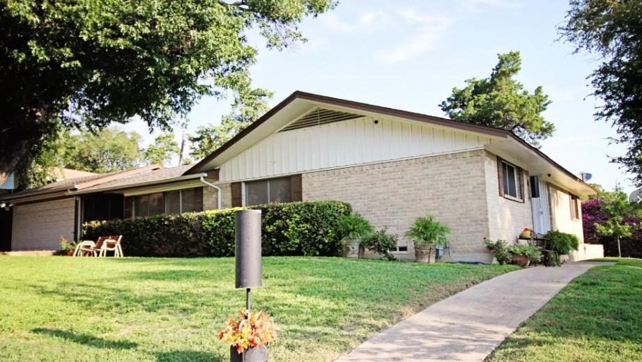 Brick ranch home with an expansive manicured lawn bordered by mature trees and established landscaping Brick ranch home with an expansive manicured lawn bordered by mature trees and established landscaping