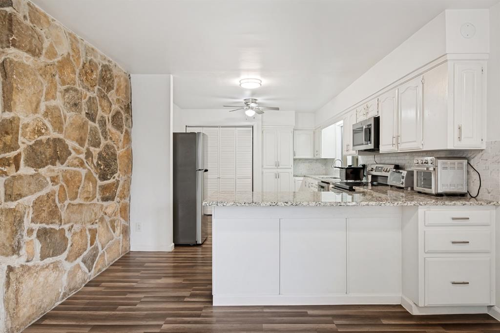 Modern kitchen featuring white cabinetry with brushed metal hardware, stainless steel appliances, and a quartz countertop with subway tile backsplash