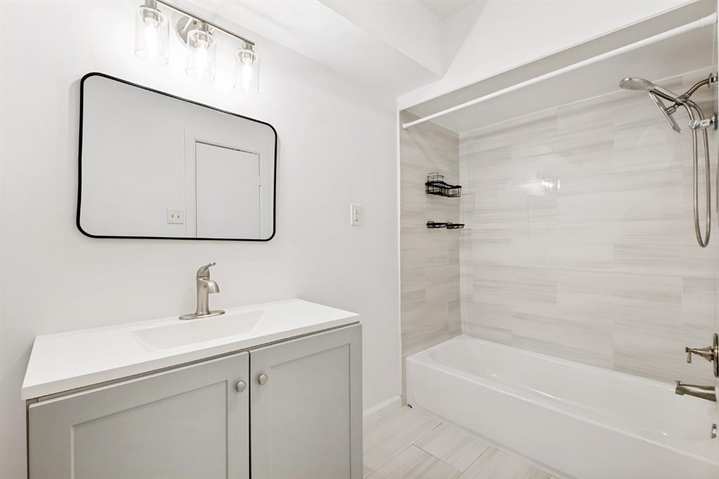 White vanity with a single basin sink, brushed nickel faucet, and a black framed rectangular mirror