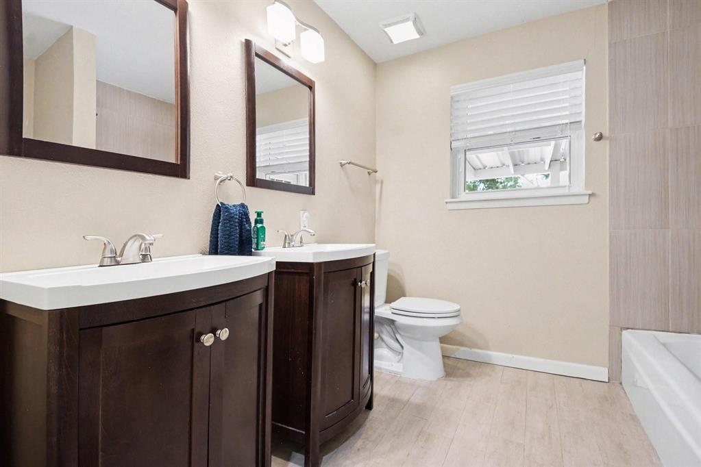 Dual wood-finish vanities with integrated sinks, brushed nickel faucets, and coordinating framed mirrors