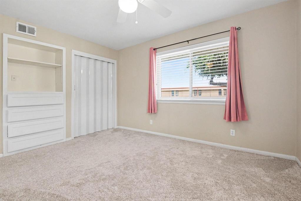 Recessed built-in shelving with drawers, accordion closet door, and light-colored carpeting