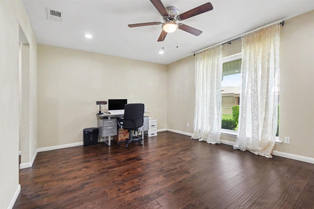 Wood-finish flooring, recessed lighting, ceiling fan with integrated light, and a large window