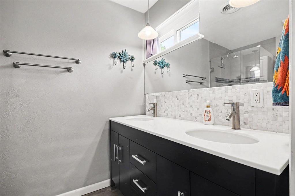 Dual vanity with white countertop, undermount sinks, and a mosaic tile backsplash