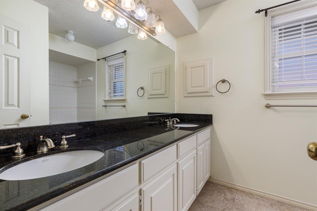 Dual vanity with dark granite-style countertop, white cabinetry, and brushed nickel fixtures