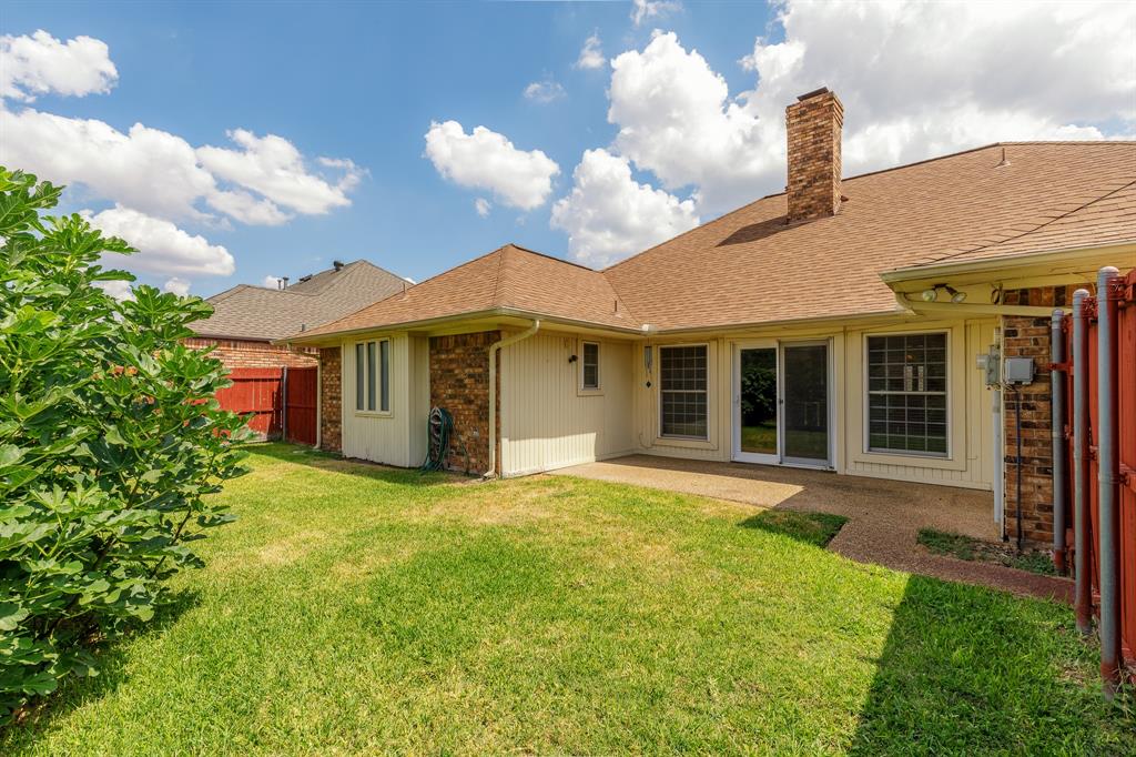 Expansive green lawn, brick exterior, composition shingle roof, sliding glass doors, and a stone chimney