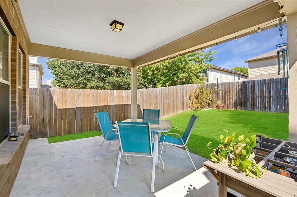 Covered patio with concrete flooring, wood privacy fence, and a manicured lawn
