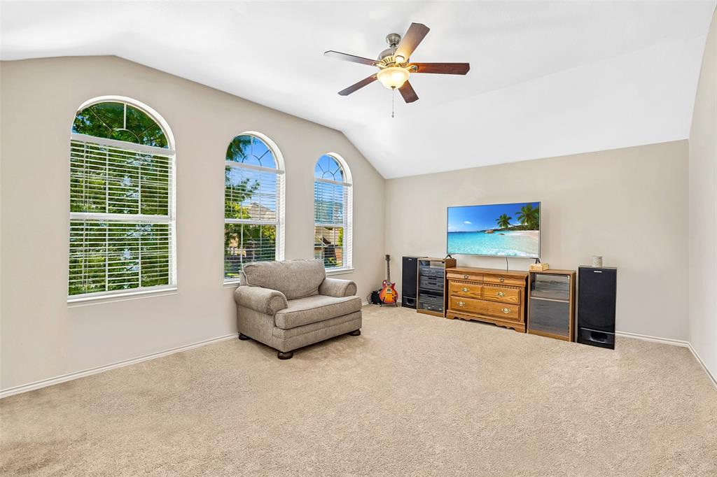 Vaulted ceilings with a ceiling fan, three arched windows, and light neutral carpeting