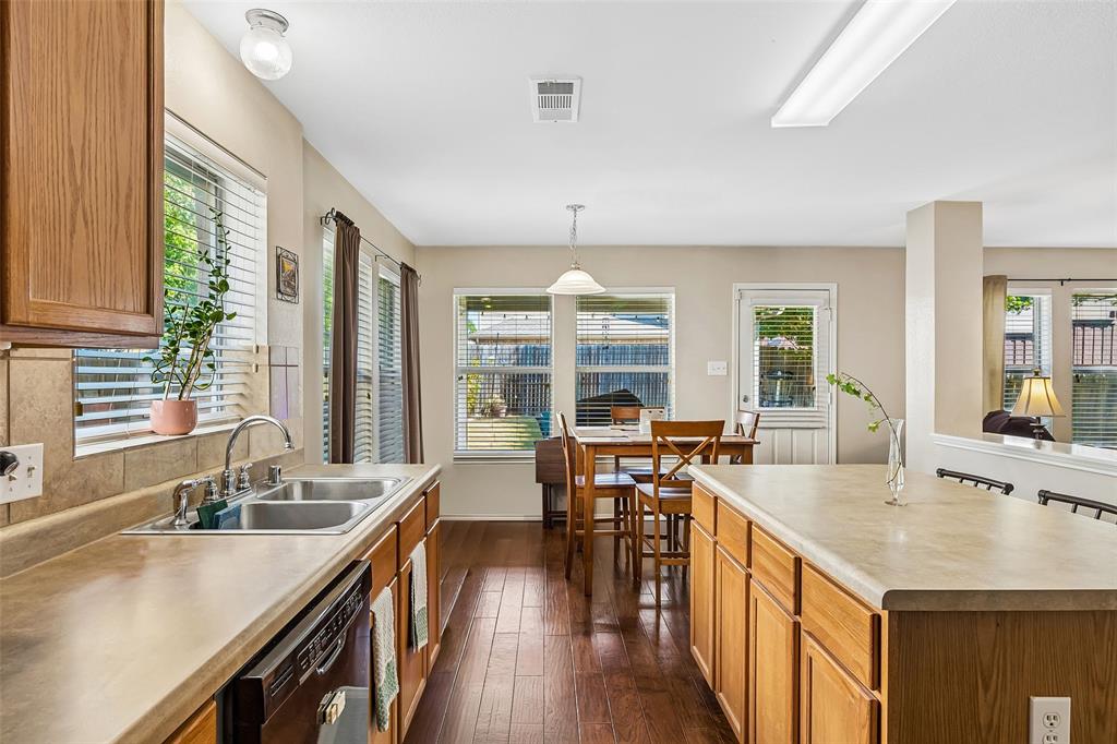 Kitchen featuring wood-finish flooring, wood cabinetry, a double basin stainless steel sink, and light-colored countertops