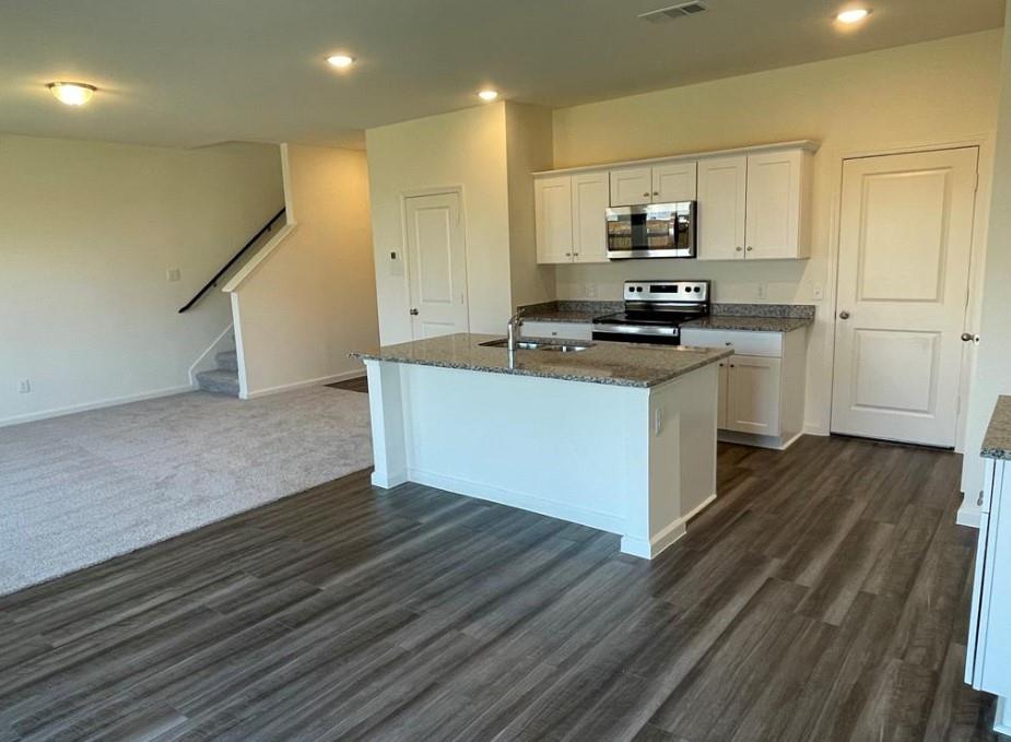 Kitchen featuring a central island, white cabinetry, integrated stainless steel microwave, and a black range