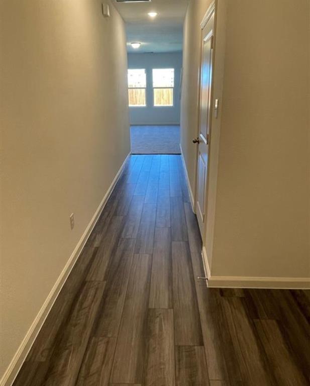 Hallway featuring wood-finish flooring, light neutral wall tones, and white trim