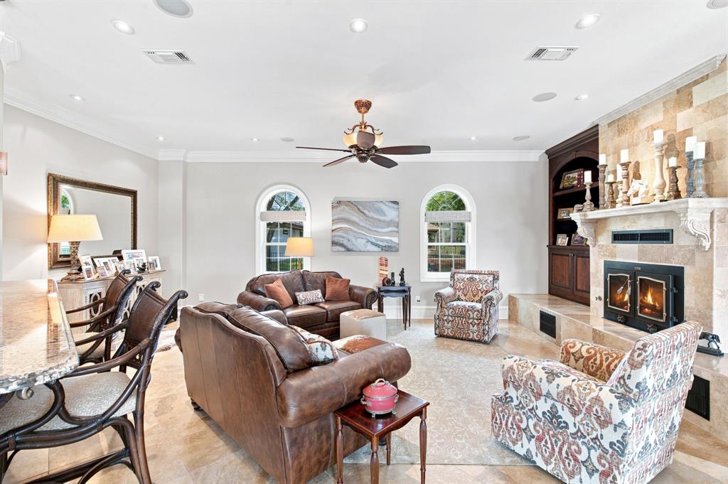 Recessed lighting, crown molding, arched windows, built-in cabinetry, and a stone fireplace with hearth