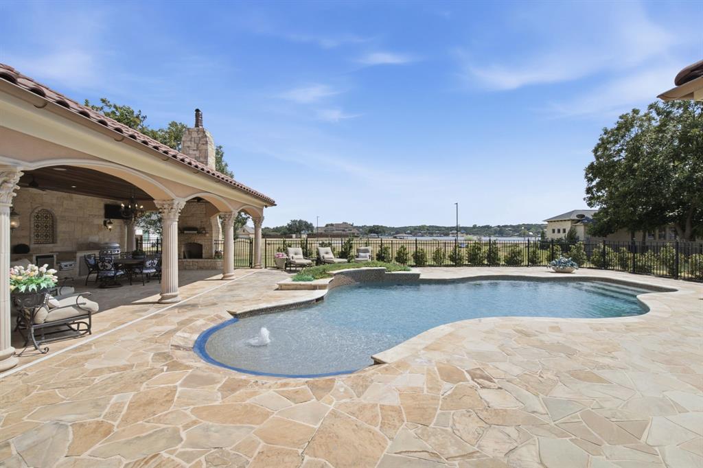 Freeform swimming pool with integrated water feature, extensive flagstone patio, covered outdoor living area, and integrated outdoor kitchen