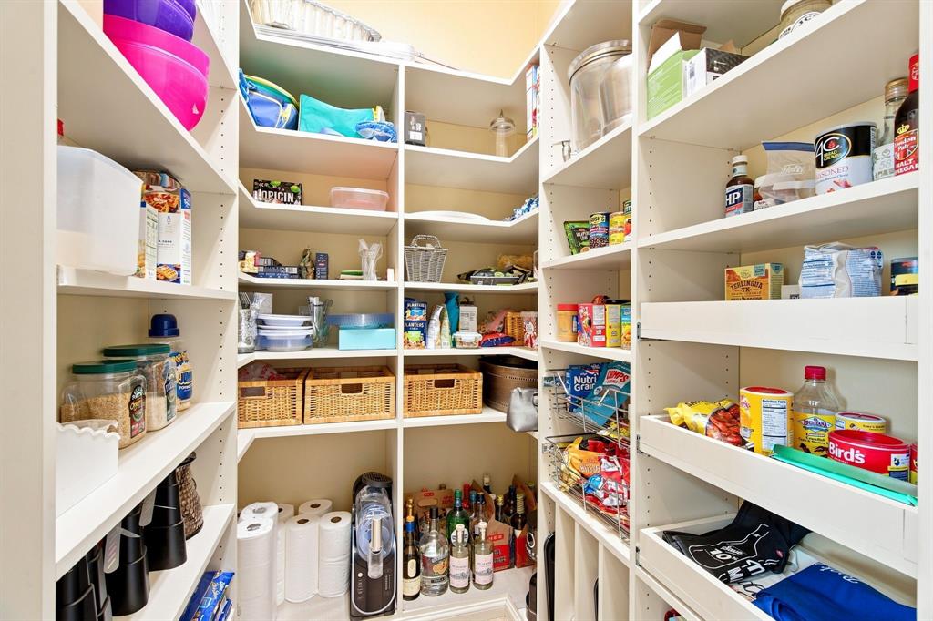 Walk-in pantry featuring extensive white shelving, multiple adjustable shelves, integrated corner shelving, and pull-out drawers