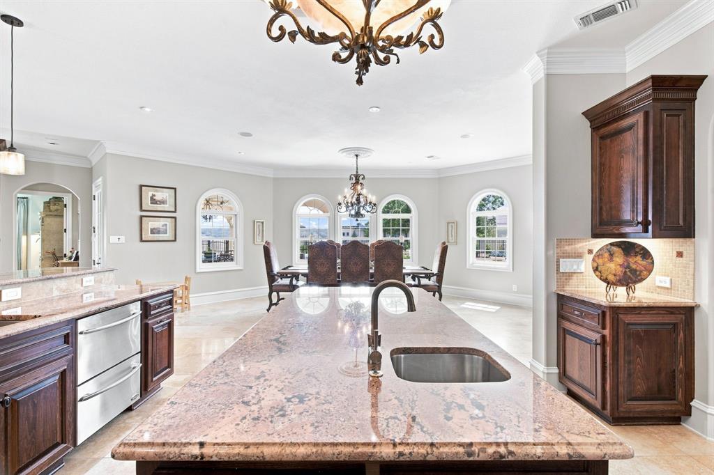 Central kitchen island with an undermount sink, granite countertops, stainless steel appliances, and dark wood cabinetry