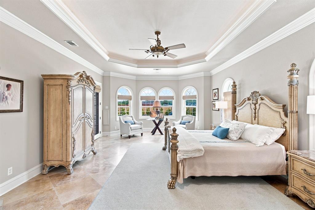 Tray ceiling with crown molding, arched windows, and tile flooring