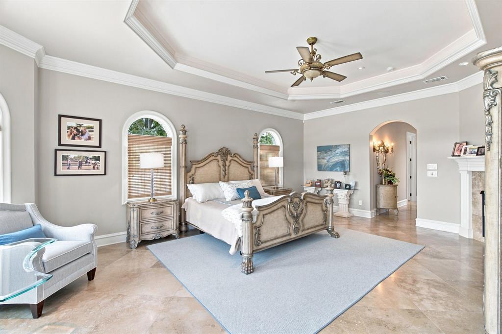 Tray ceiling with crown molding, arched windows, tile flooring, and an arched entry