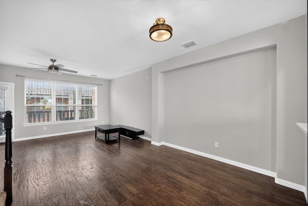 Hardwood-finish flooring, recessed wall niche, ceiling fan, and prominent window with blinds