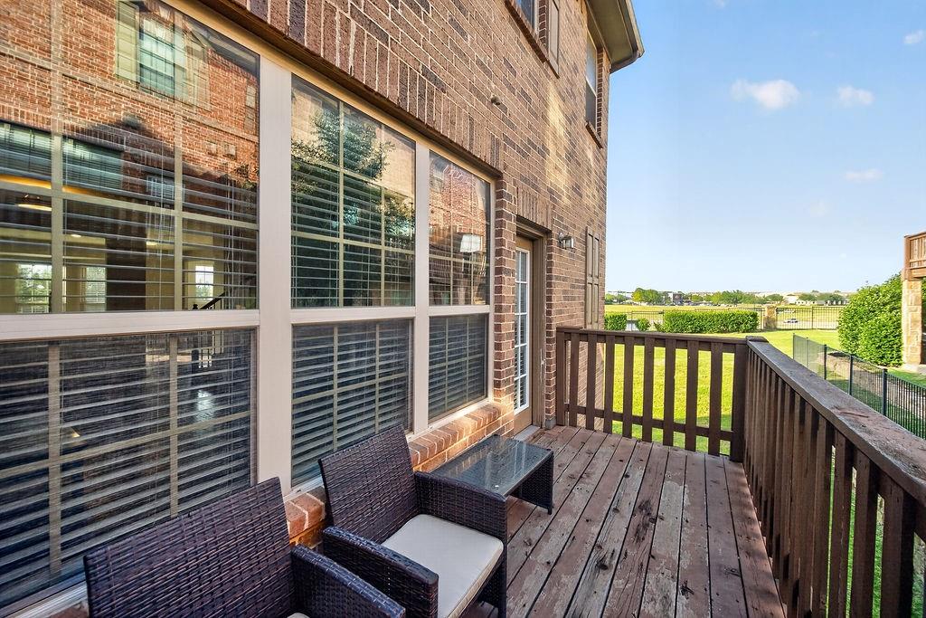 Outdoor deck with wood-finish flooring, wood railing, and brick exterior