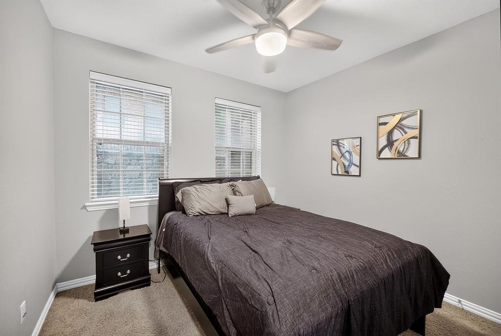 Neutral wall color, two windows with blinds, ceiling fan with light fixture, carpeted flooring, and white trim
