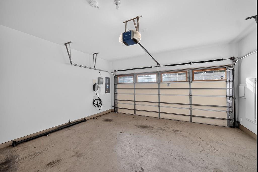 Garage featuring an automatic opener, EV charging station, and overhead storage rails