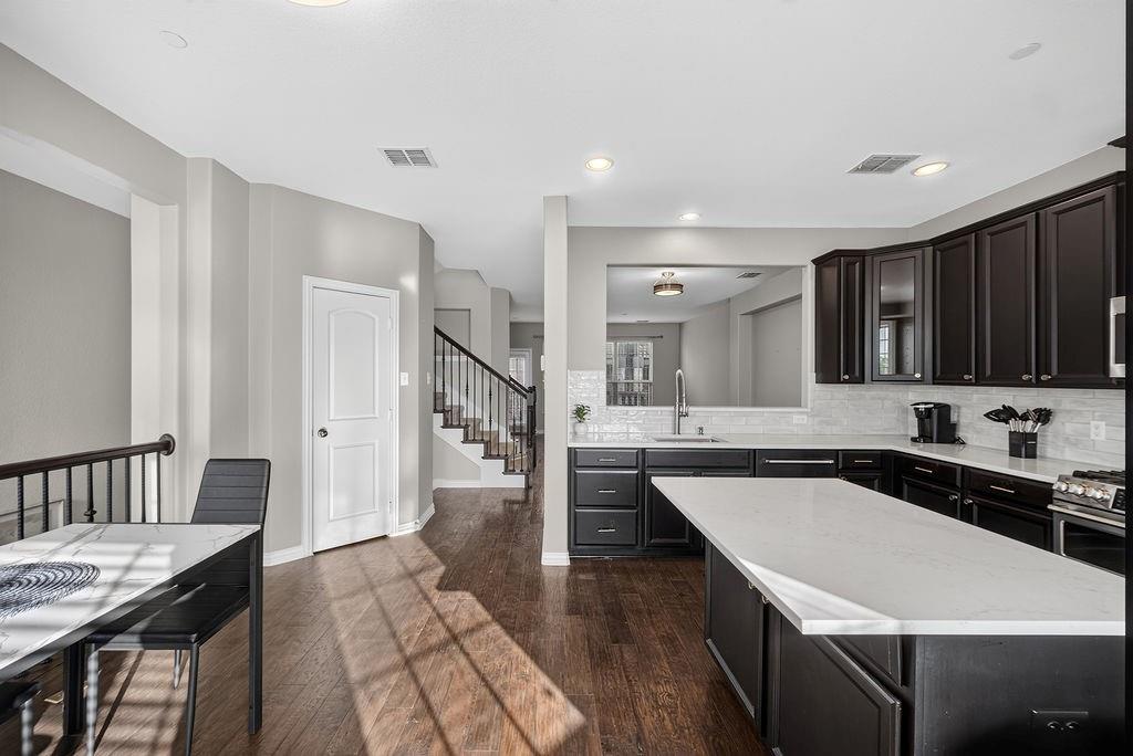 Kitchen with dark wood cabinetry, light countertops, and a full tile backsplash