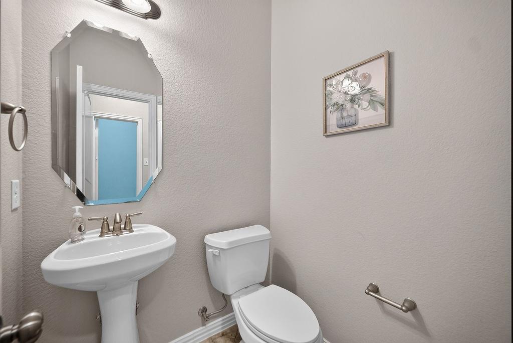 Pedestal sink with brushed nickel faucet, beveled wall mirror, and neutral wall paint