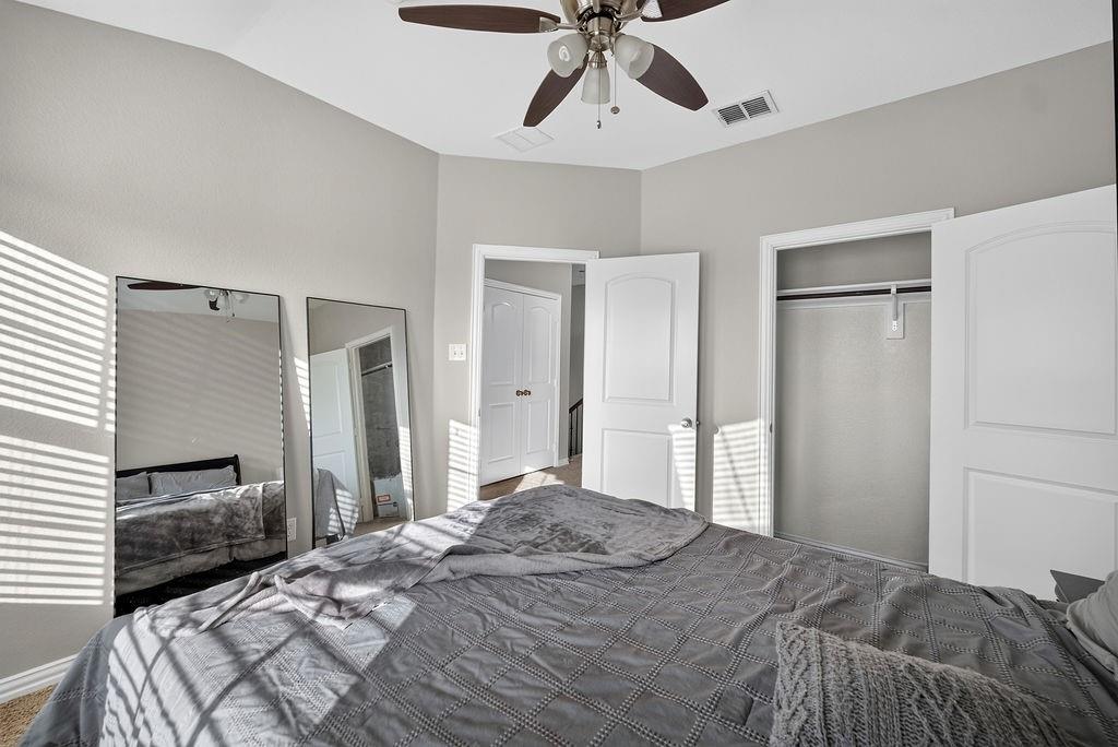 Vaulted ceiling with a ceiling fan, light gray wall paint, open closet with hanging rod, and two paneled interior doors