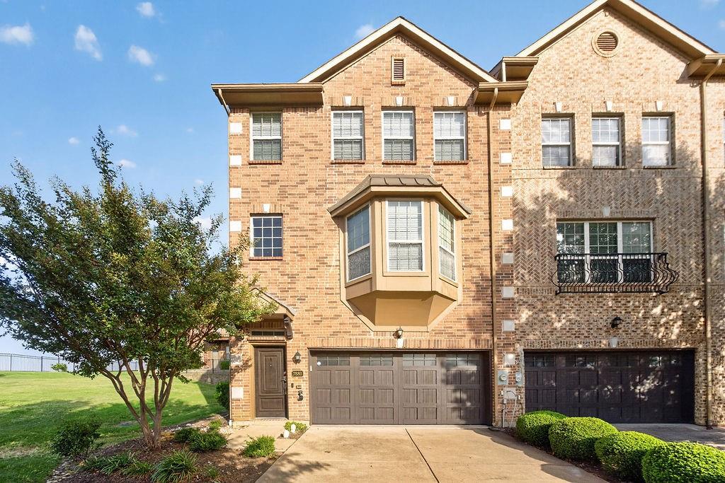 Brick exterior with a prominent bay window, two-car garage, and an ornamental balcony