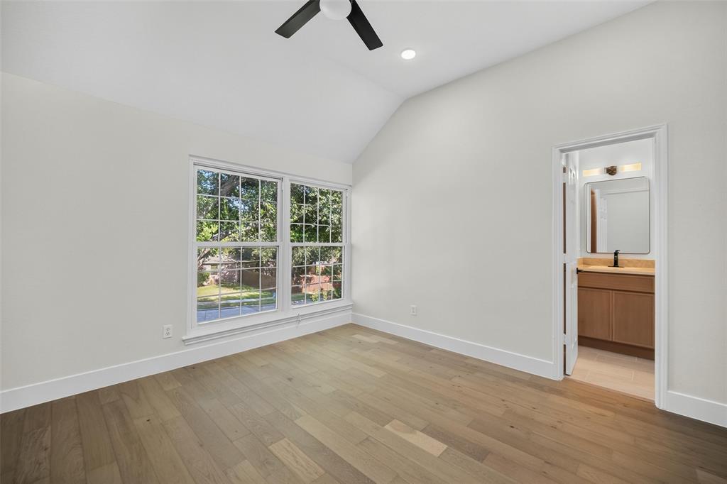 Vaulted ceiling with a ceiling fan, wood-finish flooring, and a double window