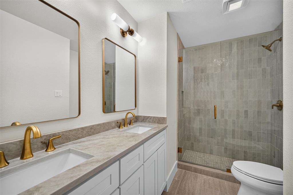 Double vanity with undermount sinks, gold-tone fixtures, and framed mirrors