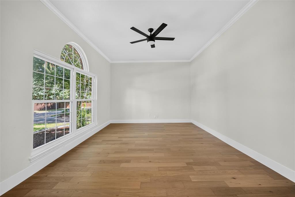Wood-finish flooring, crown molding, and a modern ceiling fan