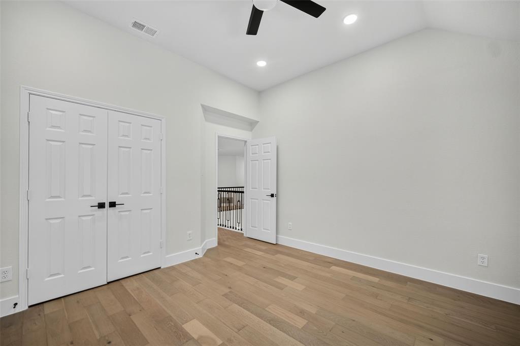 Vaulted ceiling, recessed lighting, wood-finish flooring, two-panel interior doors, and a ceiling fan