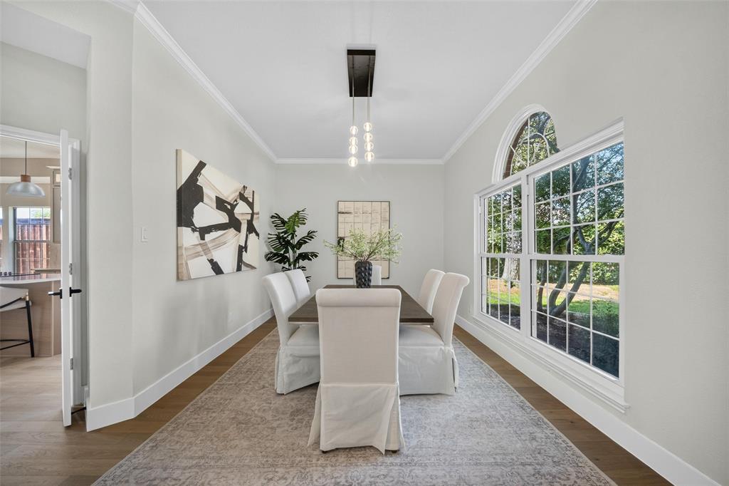 Wood-finish flooring, crown molding, and a chandelier with glass globes