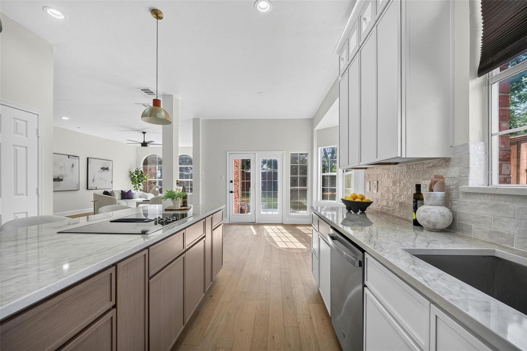 Kitchen featuring light wood-finish flooring, recessed lighting, an expansive island with a built-in cooktop, light-toned countertops, and white cabinetry