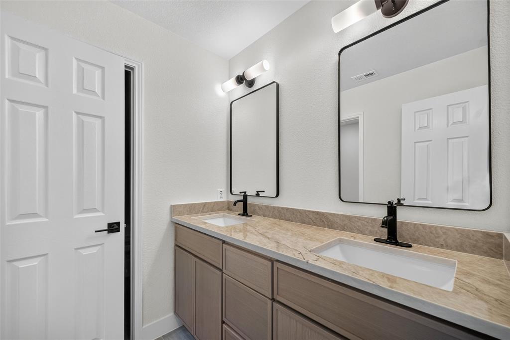 Dual rectangular vessel sinks with matte black faucets, set into a stone-finish countertop
