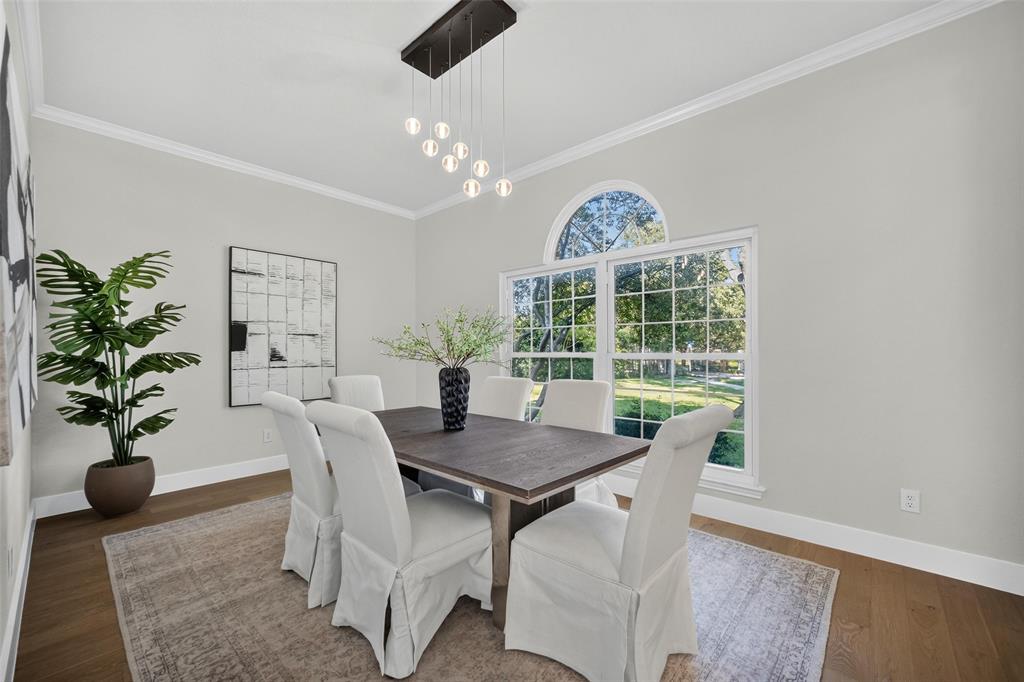 Wood-finish flooring, crown molding, and a contemporary chandelier Wood-finish flooring, crown molding, and a contemporary chandelier