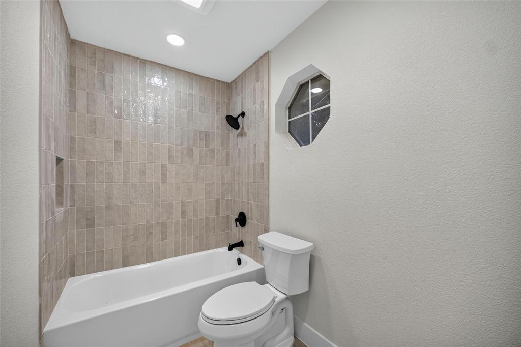 Bathtub with tiled surround, recessed shower niche, and matte black fixtures