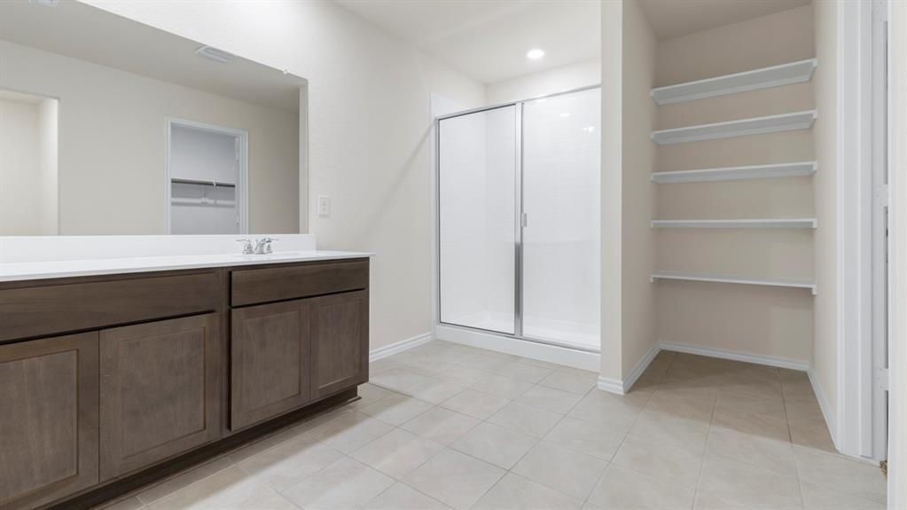Spacious bathroom featuring a dark wood-finish vanity with a white countertop, large mirror, and a walk-in shower with sliding glass doors Spacious bathroom featuring a dark wood-finish vanity with a white countertop, large mirror, and a walk-in shower with sliding glass doors