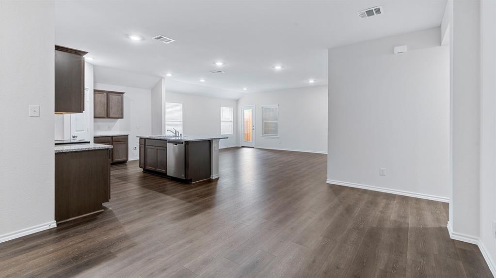 Spacious open-concept layout with wood-finish flooring, recessed lighting, and a kitchen island with built-in appliances