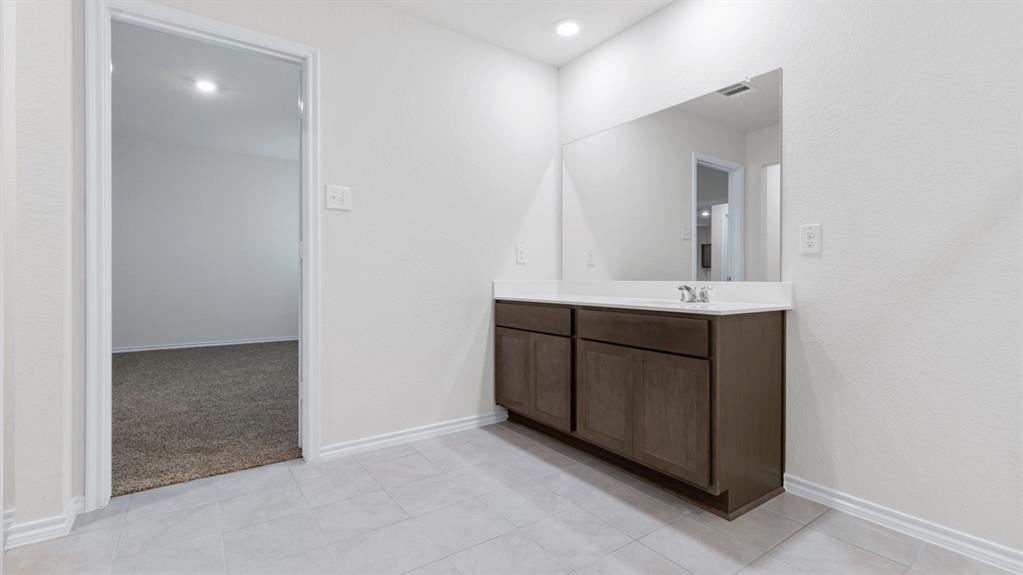 Bathroom vanity with wood-finish cabinetry, integrated sink, and a large wall-mounted mirror Bathroom vanity with wood-finish cabinetry, integrated sink, and a large wall-mounted mirror