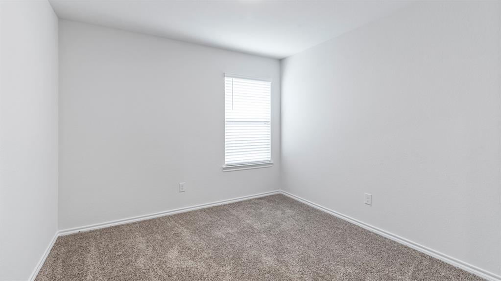 Neutral wall tones, gray carpeting, and a single window with blinds