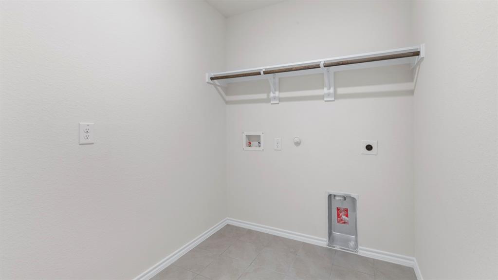 Laundry area featuring a hanging rod, wall-mounted shelf, and tile flooring