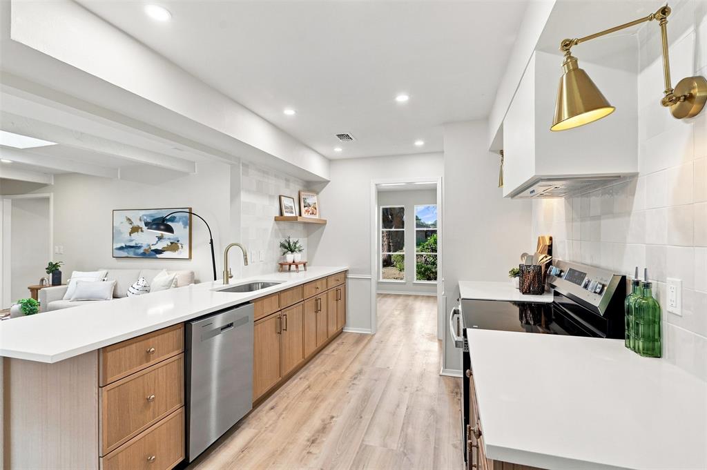 Contemporary kitchen featuring a stainless steel dishwasher, white countertops, wood-finish flooring, and recessed lighting