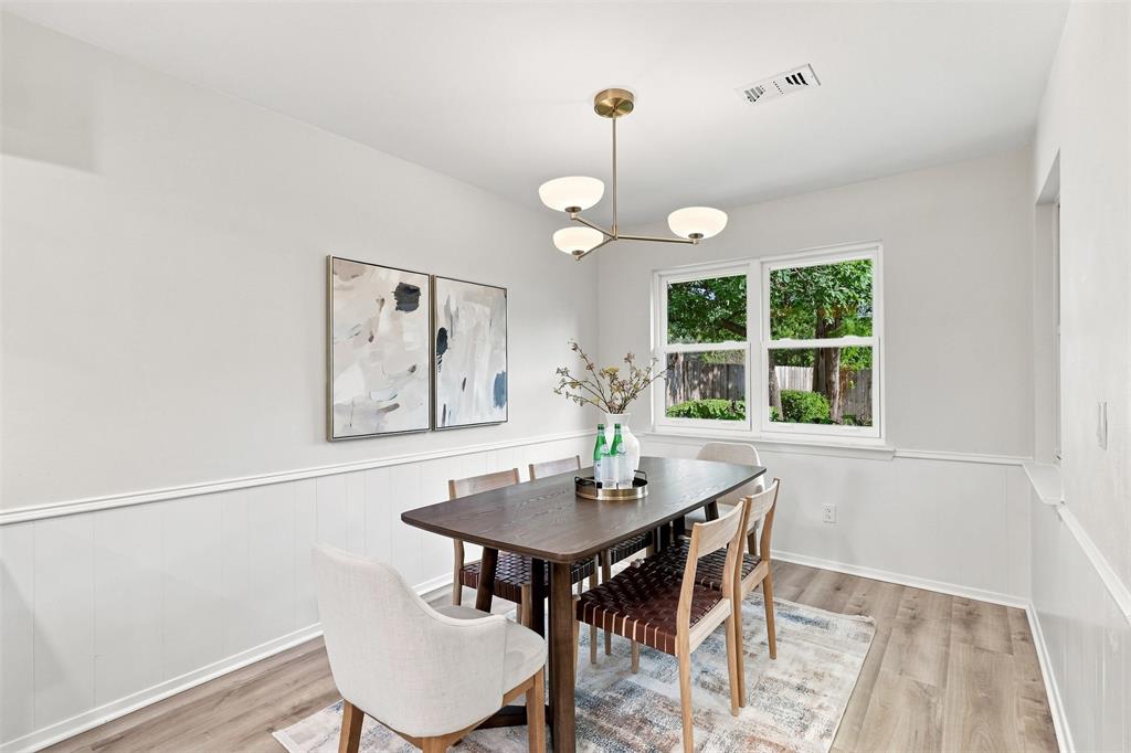 Wood-finish flooring, white paneled wainscoting, white walls, and a multi-globe chandelier