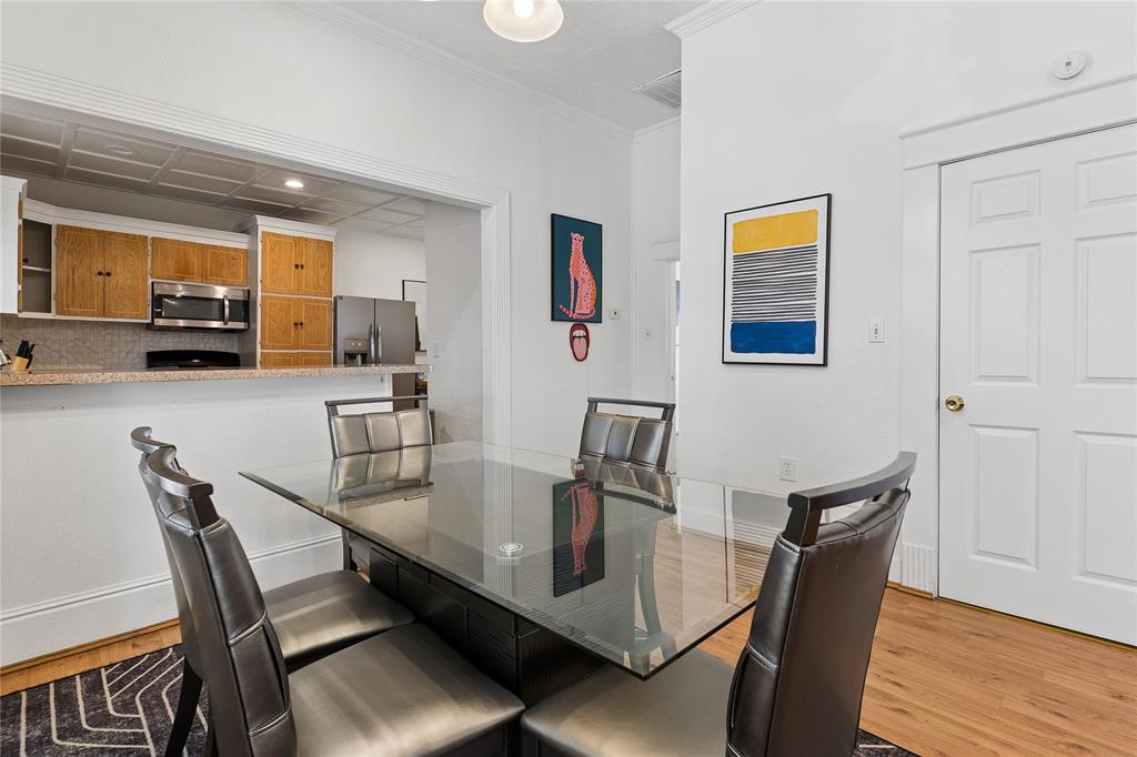 Dining area featuring a pass-through window to the kitchen, wood-finish flooring, and crown molding