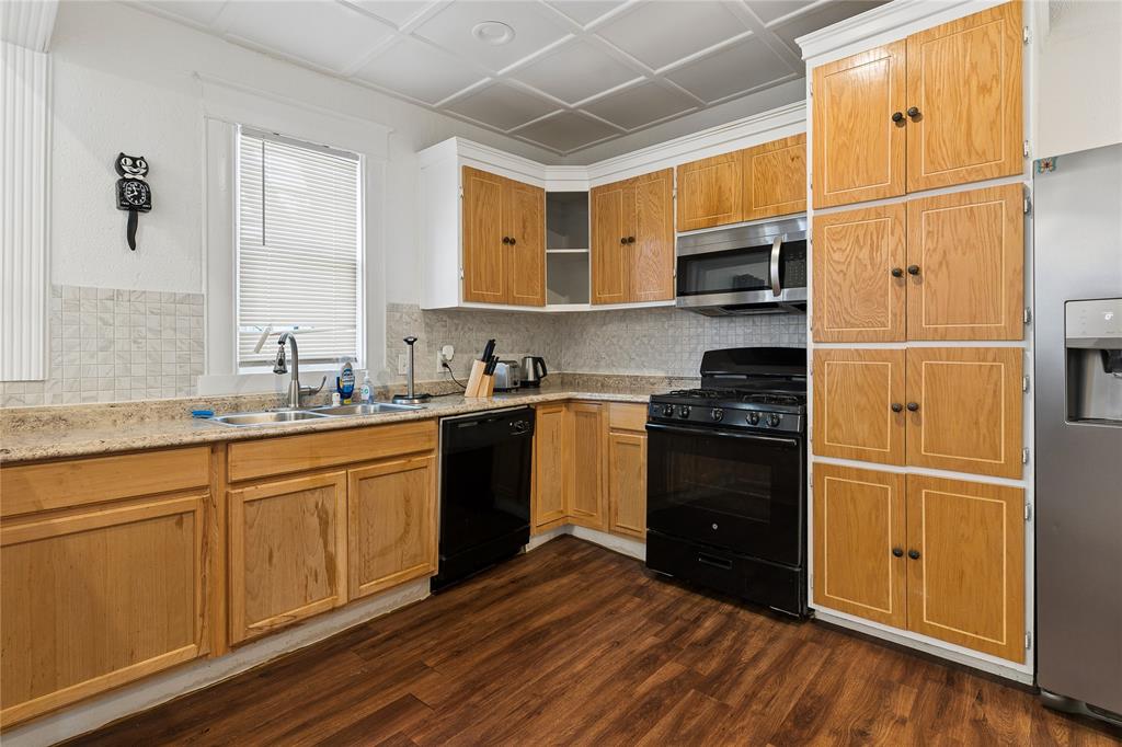 Kitchen featuring wood-finish cabinetry, granite-style countertops, stainless steel appliances, and wood-finish flooring