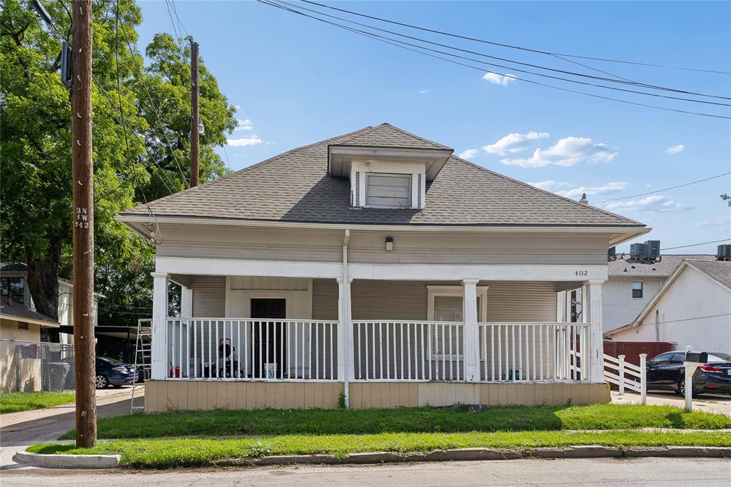 Gable roof with dormer window, full-width front porch, white porch railing, and light-colored siding