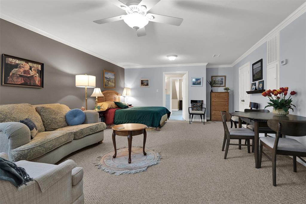 Open-concept room featuring carpeting, crown molding, a ceiling fan, and distinct wall colors